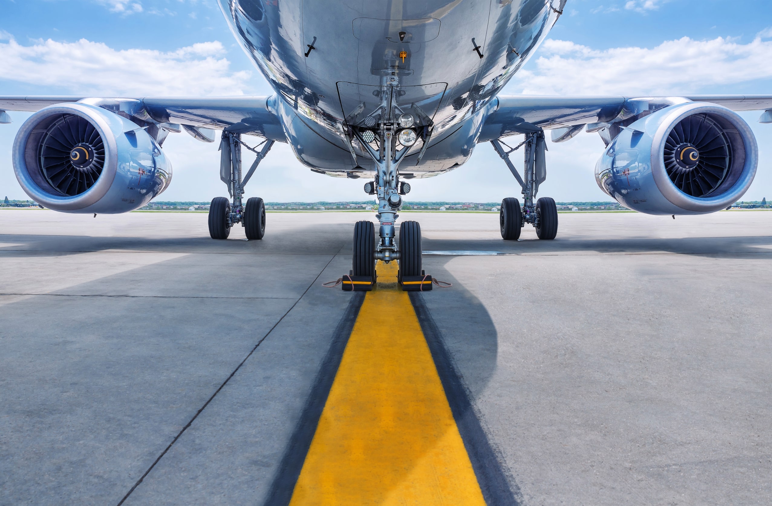 Close-up view of an airplane’s undercarriage and engines on the tarmac under a clear sky, representing air travel and TSA-related rules for Bluetooth speakers in 2025.