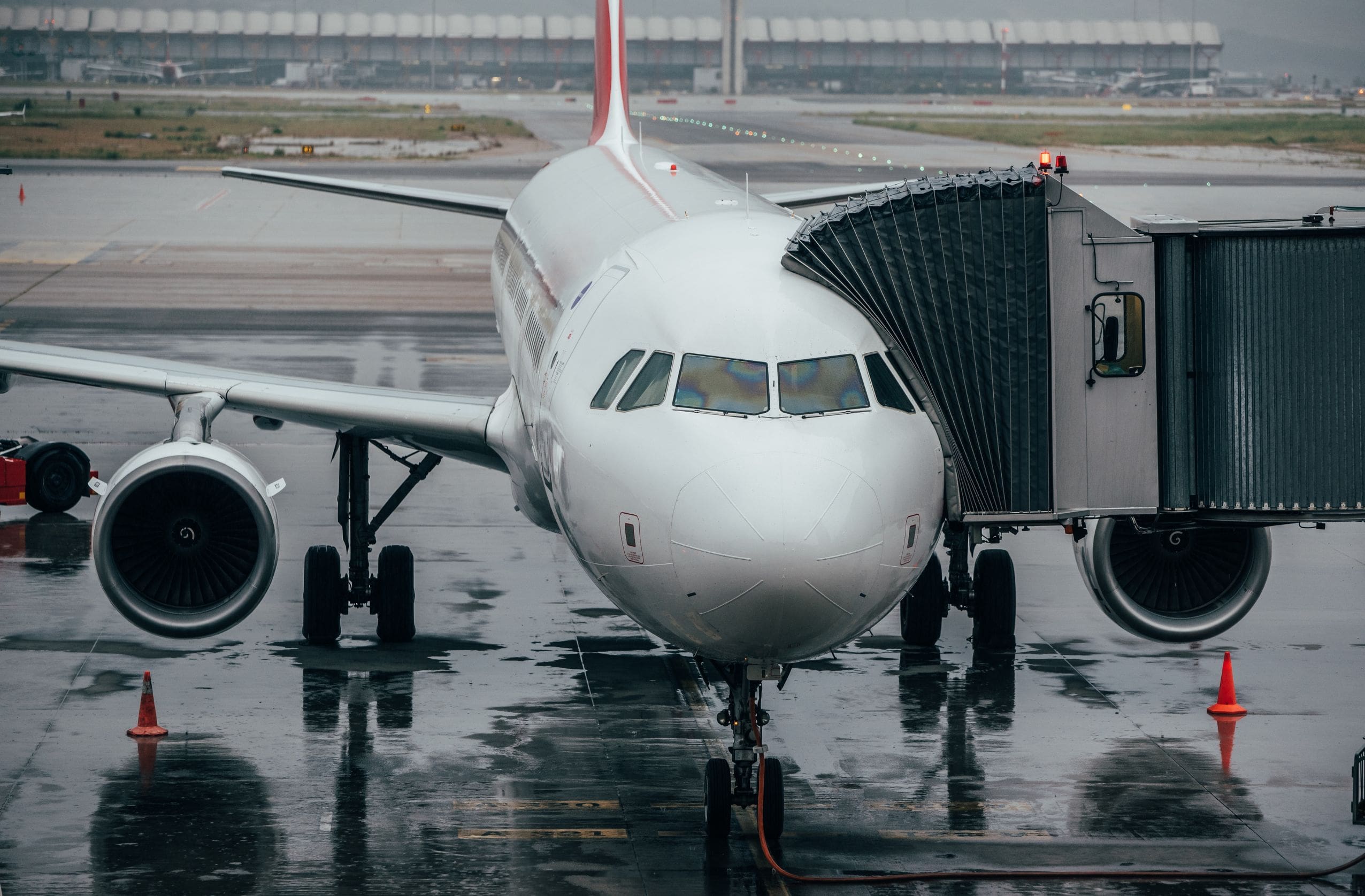 Commercial airplane at the gate on a rainy day, ready for boarding, reinforcing the theme of travel preparation and TSA rules for Bluetooth speakers in 2025.